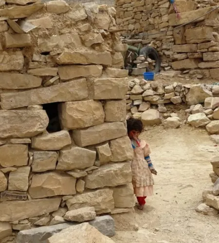 Verwahrlostes Kind neben Steinhaus im Jemen