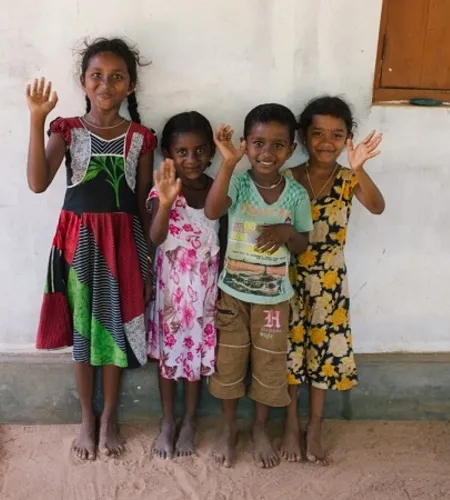 Kinder vor einer Hauswand winken in die Kamera