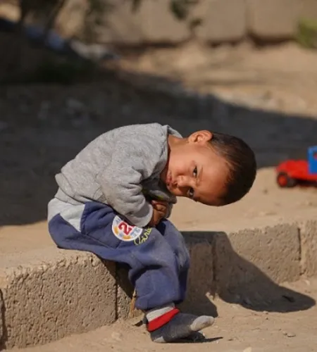 Syrischer Junge mit Spielzeugauto in einem Flüchtlingscamp im Irak