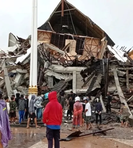 Menschen stehen vor zerstörten Häusern in Sulawesi