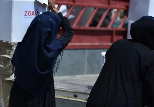 Verhüllte Frau trägt ein Nahrungsmittelpaket von ZOA