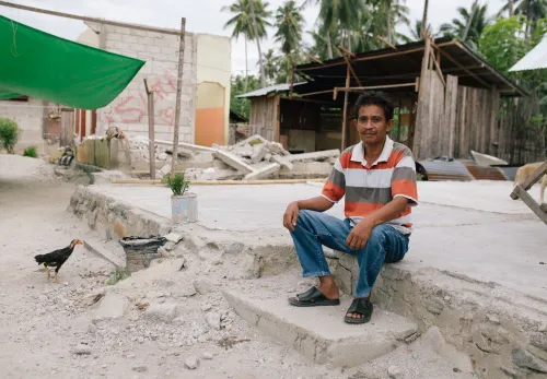 Tasrudin bij de puinhopen van zijn huis na de verwoestende aardbeving op Sulawesi in 2018